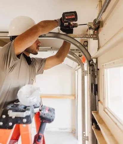 Technician inspecting and repairing a garage door